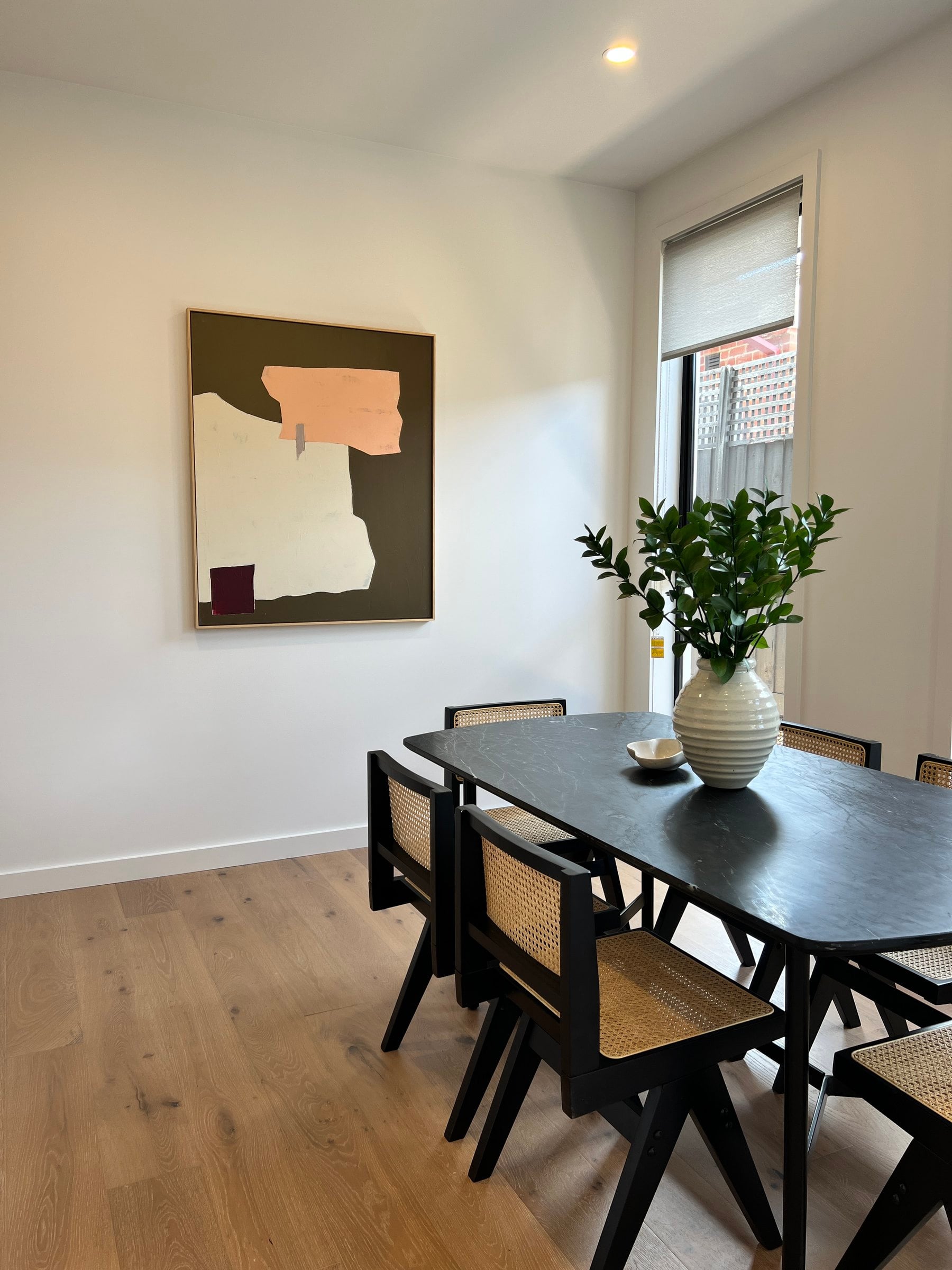Dining room with a table and cane-backed chairs beneath an abstract canvas, Hampton