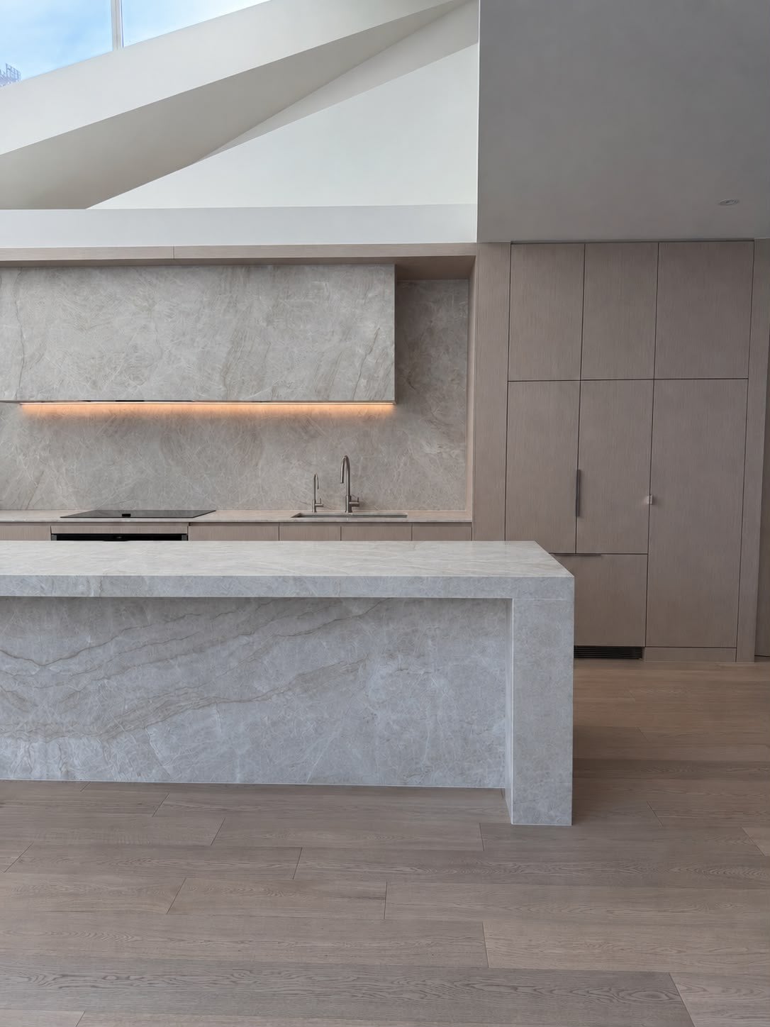 Kitchen with a stone waterfall island and a lit stone rangehood, Port Melbourne