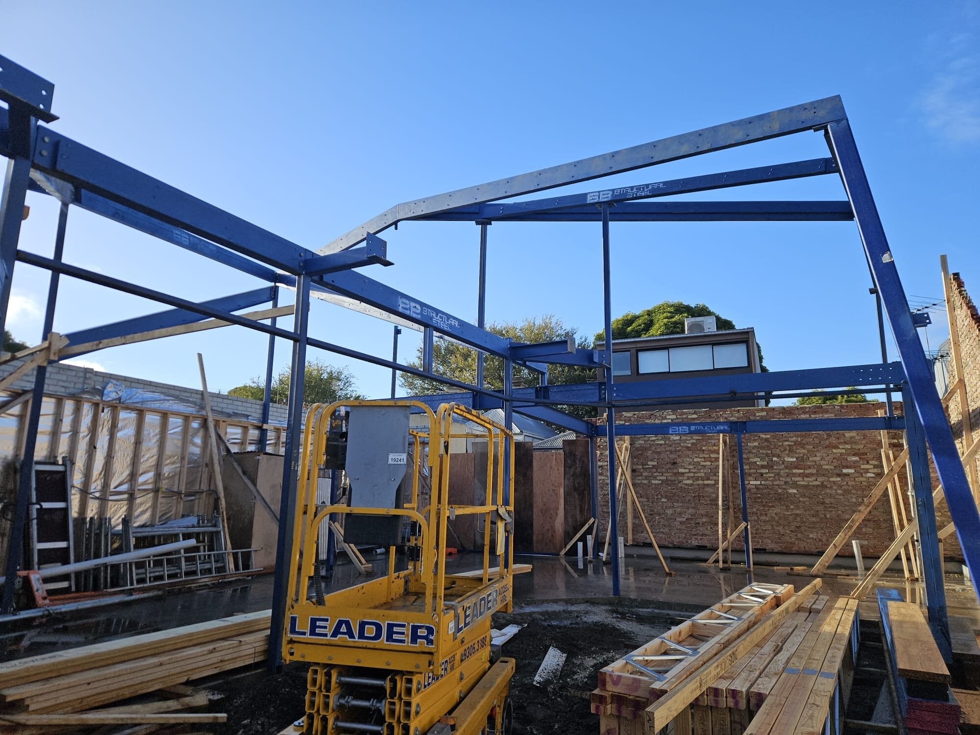 Blue steel frame going up behind the cottage, Port Melbourne