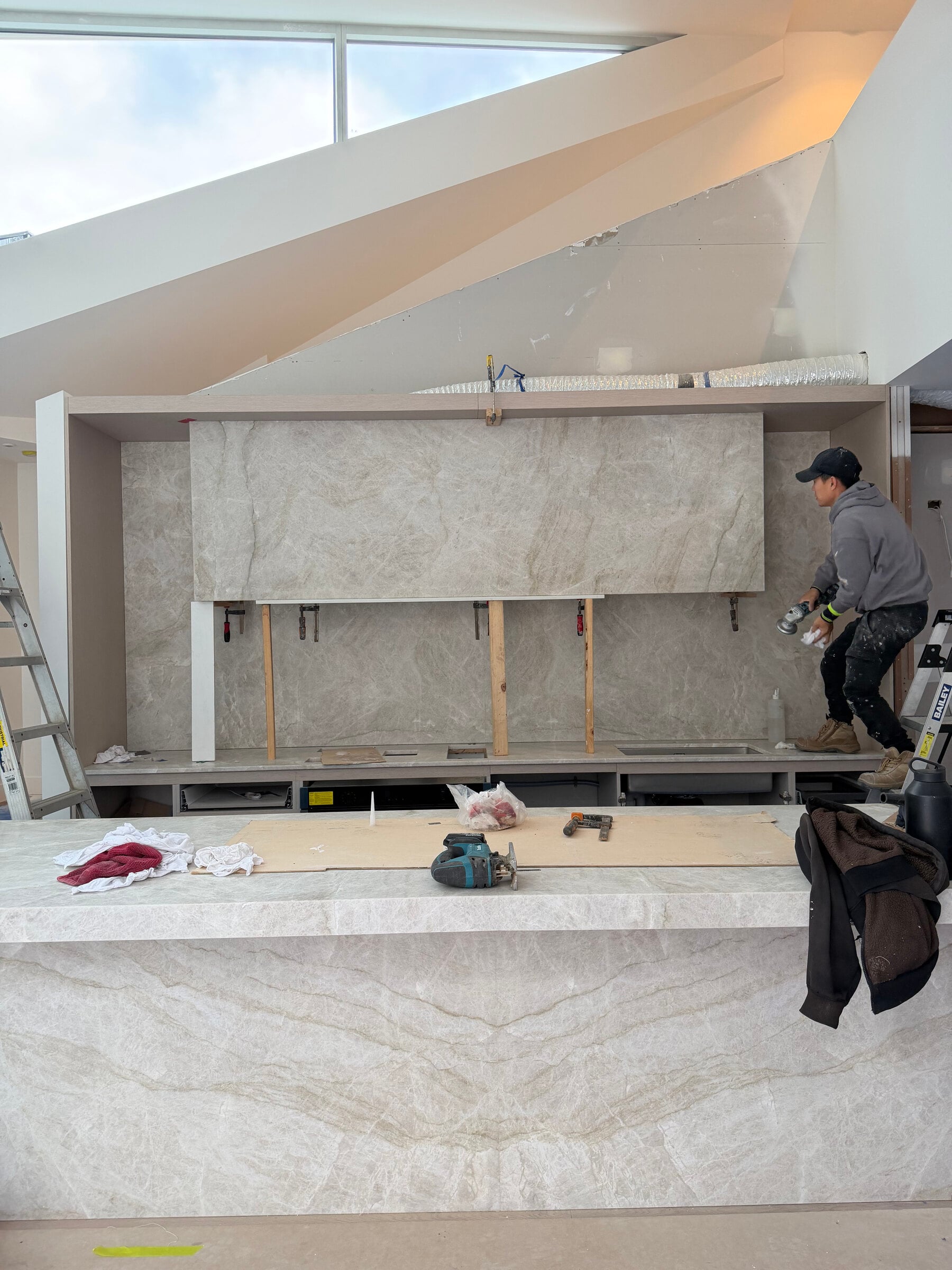 Stone rangehood panel being fitted above the kitchen bench during the build, Port Melbourne