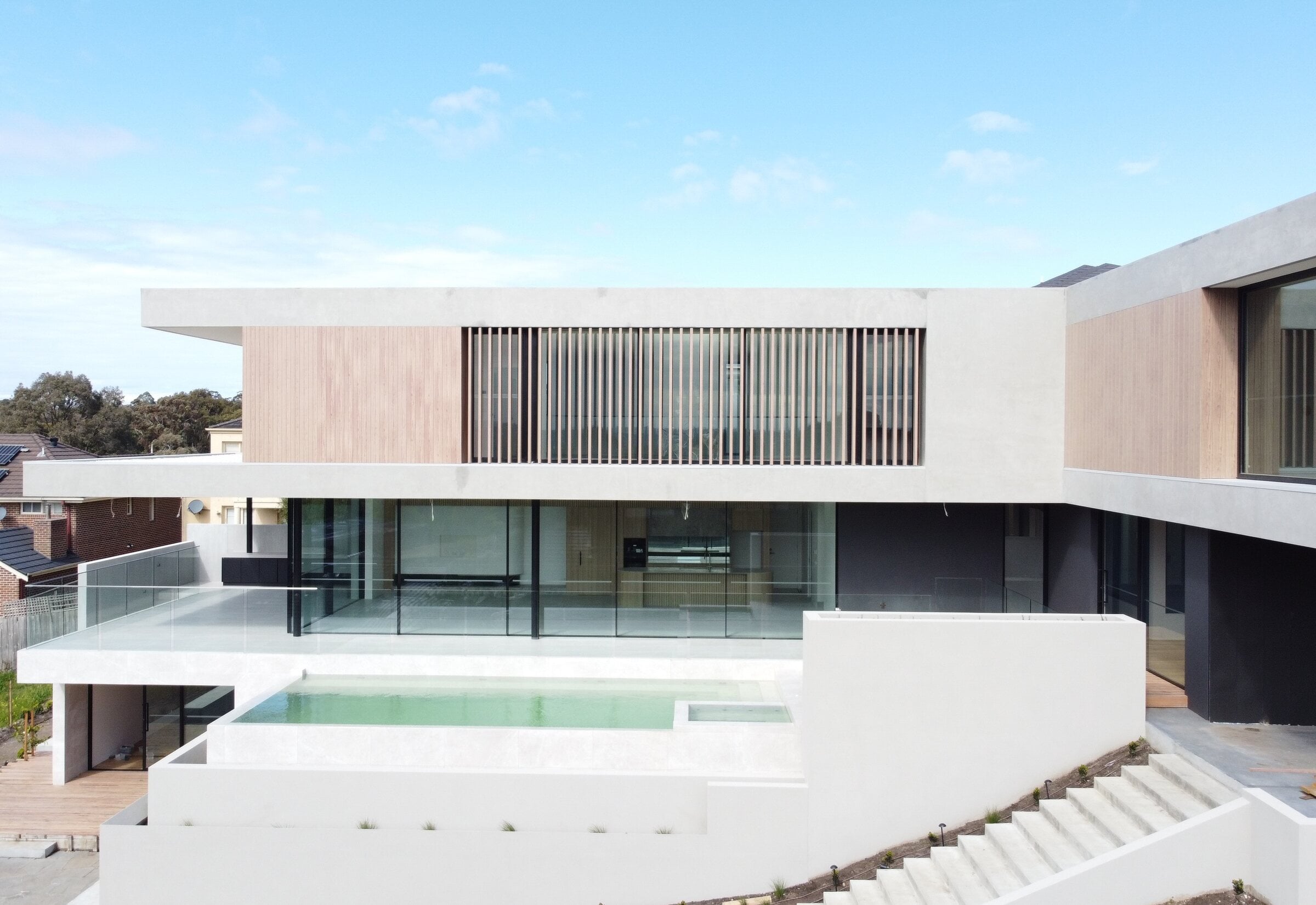 Architectural new build with timber battens over a glazed lower level and a pool, Wheelers Hill